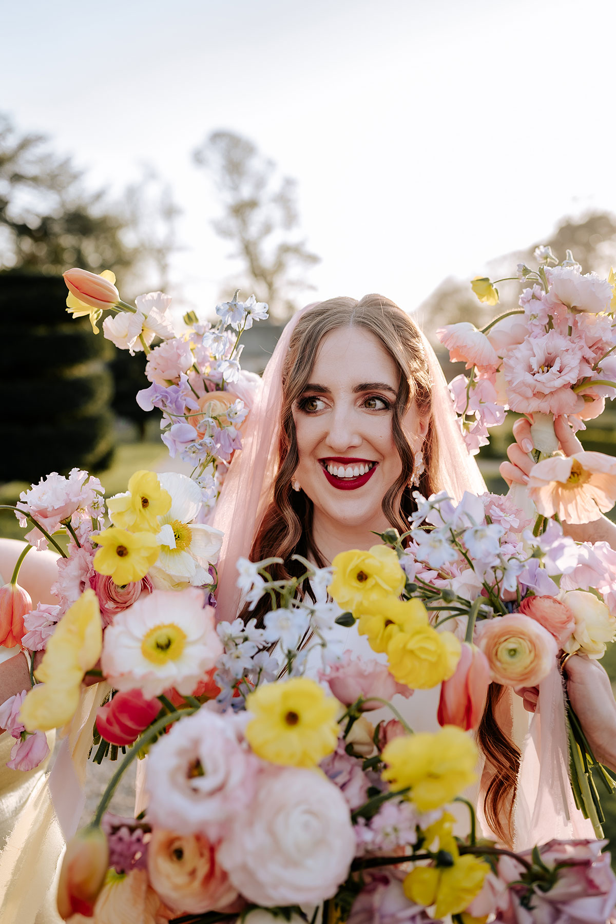 a bride framed by lots of colourful pastel wedding bouquets