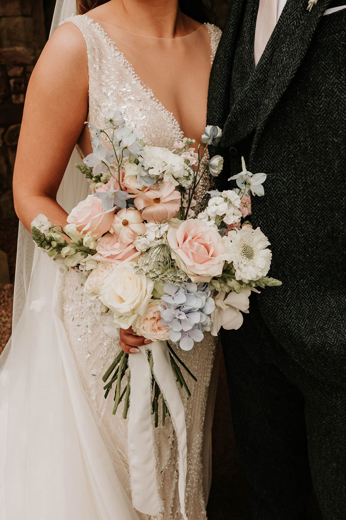 a close up of a bridal bouquet of pale pink, blue and white flowers