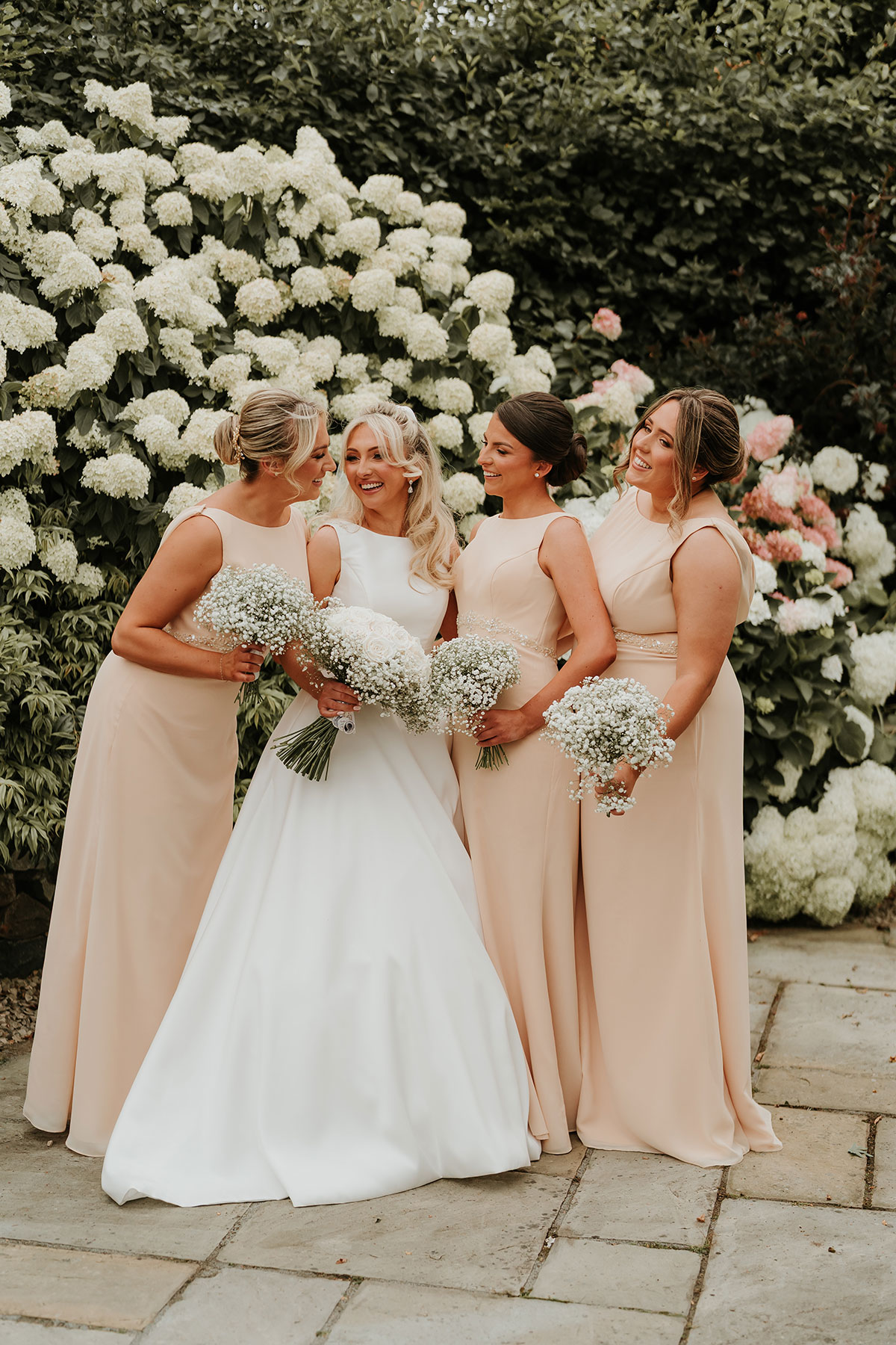 Bride with bridesmaids in peach dresses holding bouquets at Ingliston Country Club wedding