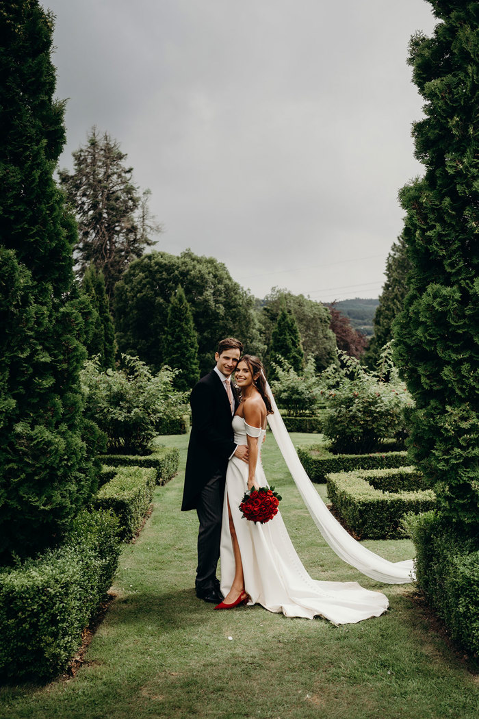 a smiling bride and groom posing for a picture in a garden at Achnagairn Castle