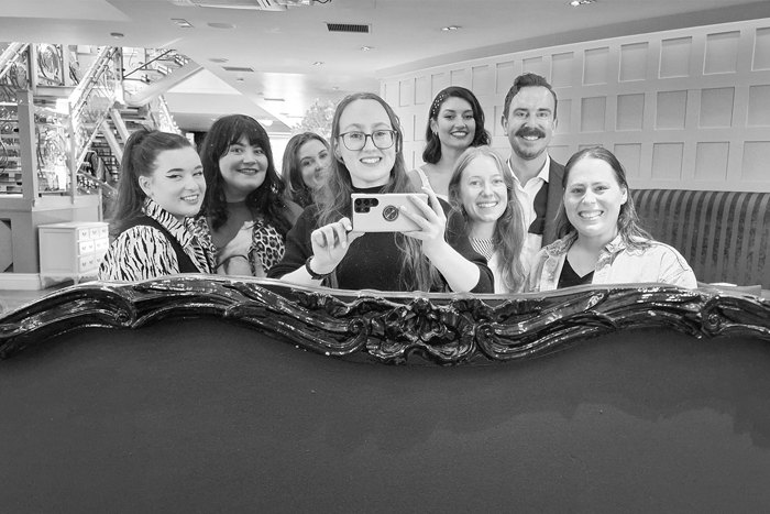 A group of people taking a photo in an ornate mirror with a phone