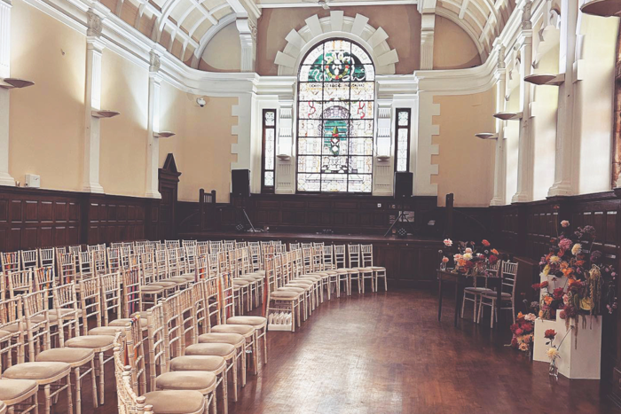 wedding layout with white and cream chairs in rows facing table with flowers