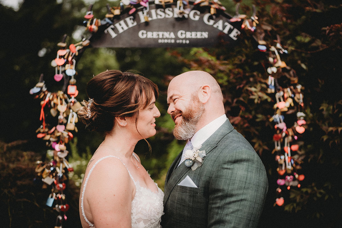 Bride and groom beneath the famous Kissing Gate at Gretna Green after their Scottish wedding ceremony.