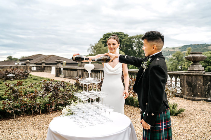 bride and groom pours champagne into tower of glasses at mar hall