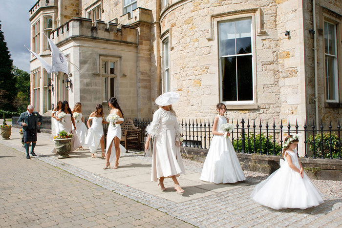 a group of people wearing wedding attire walking outside Crossbasket Castle.