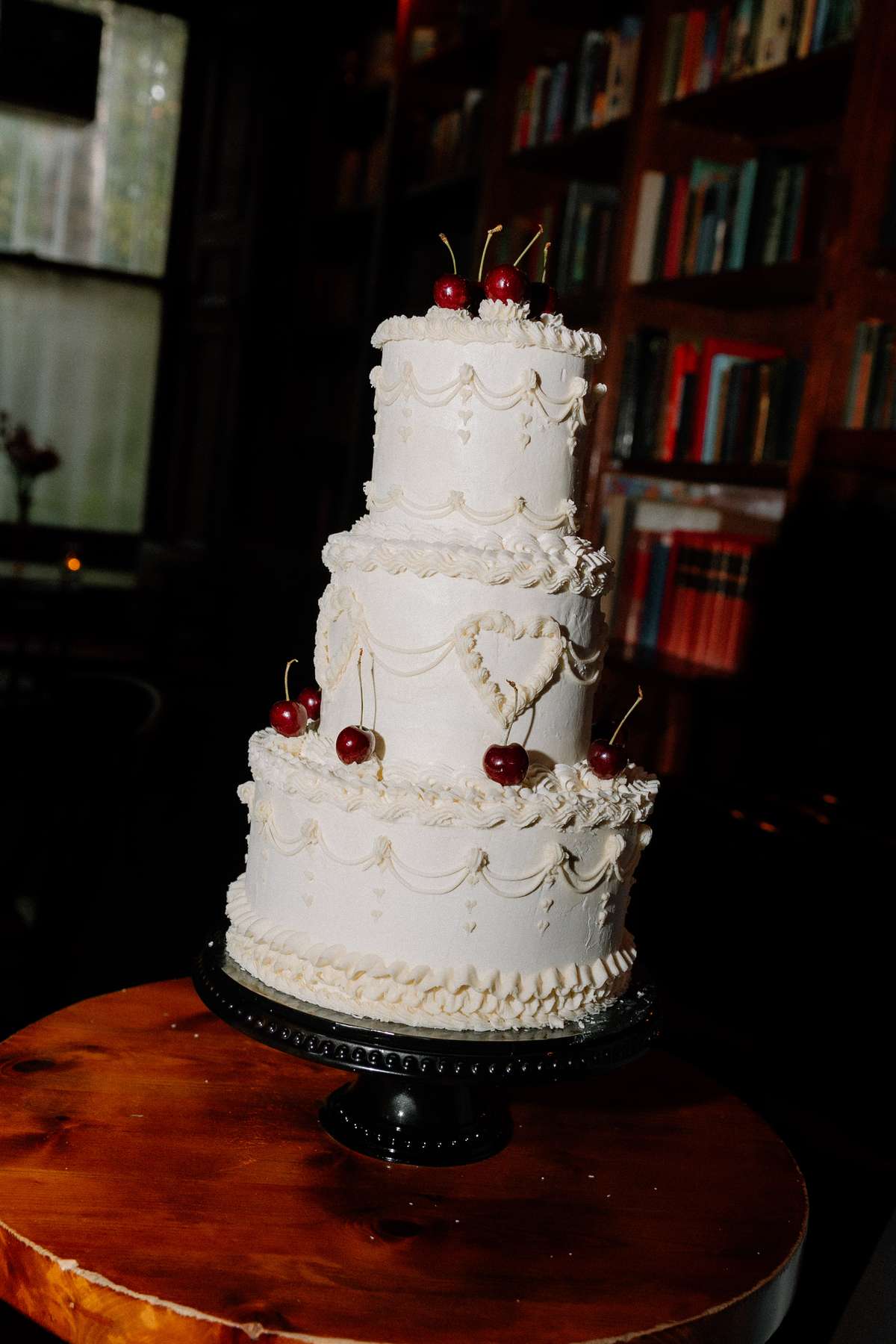 Three-tier white wedding cake with vintage-style Lambeth piping, heart detailing and cherries at Prestonfield House.