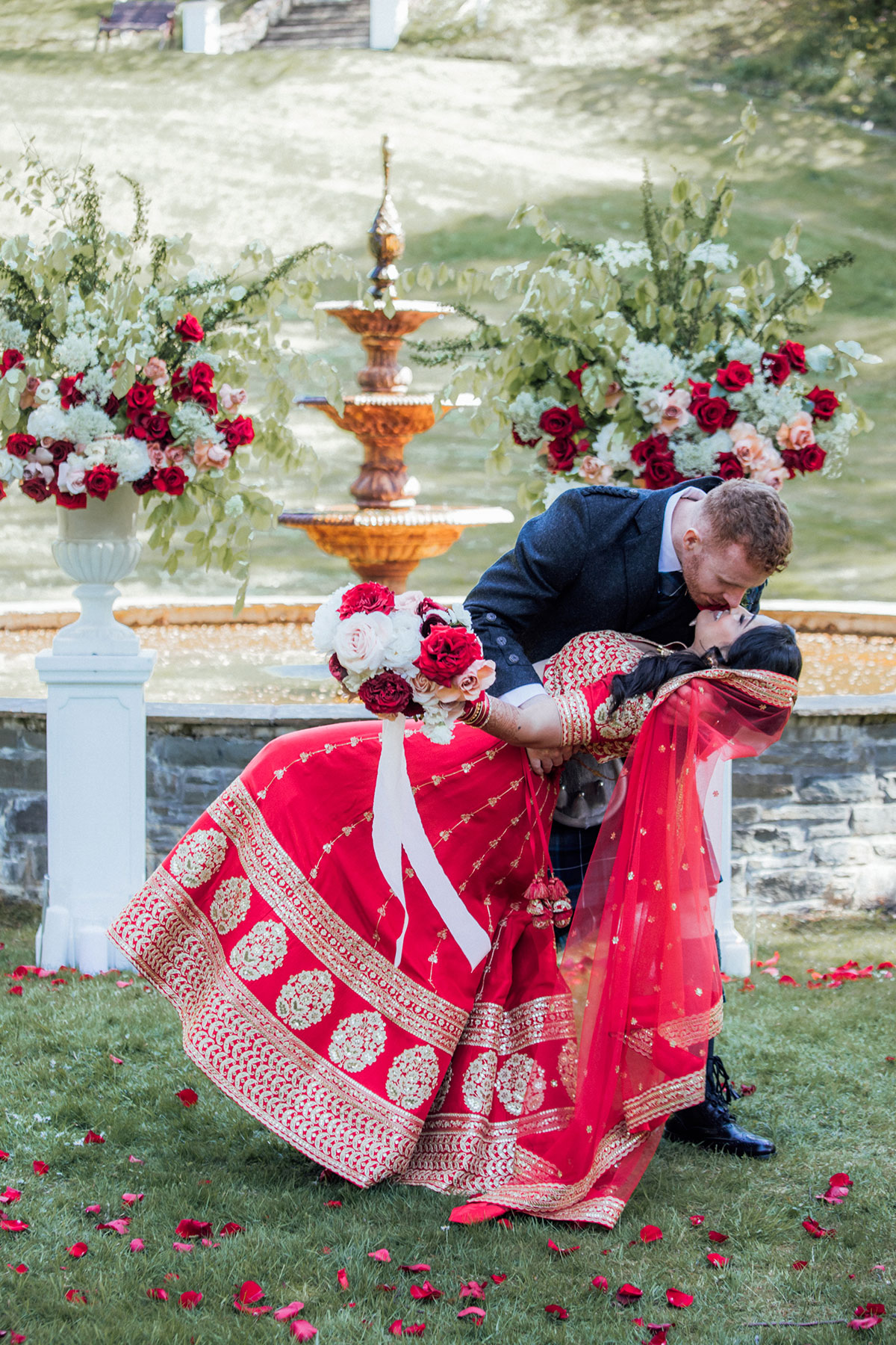 Bride and groom sharing a romantic kiss in front of the fountain at Atholl Palace Hotel after their outdoor wedding ceremony