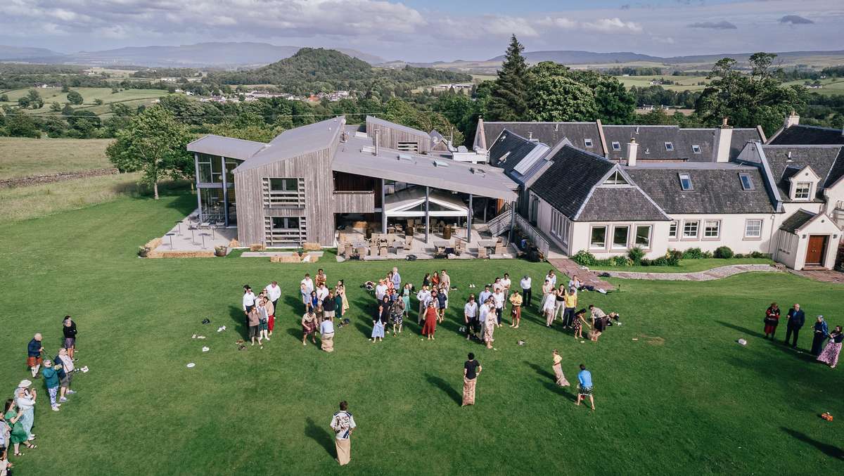 Drone view of wedding guests gathered on the lawn outside Ardoch Loch Lomond