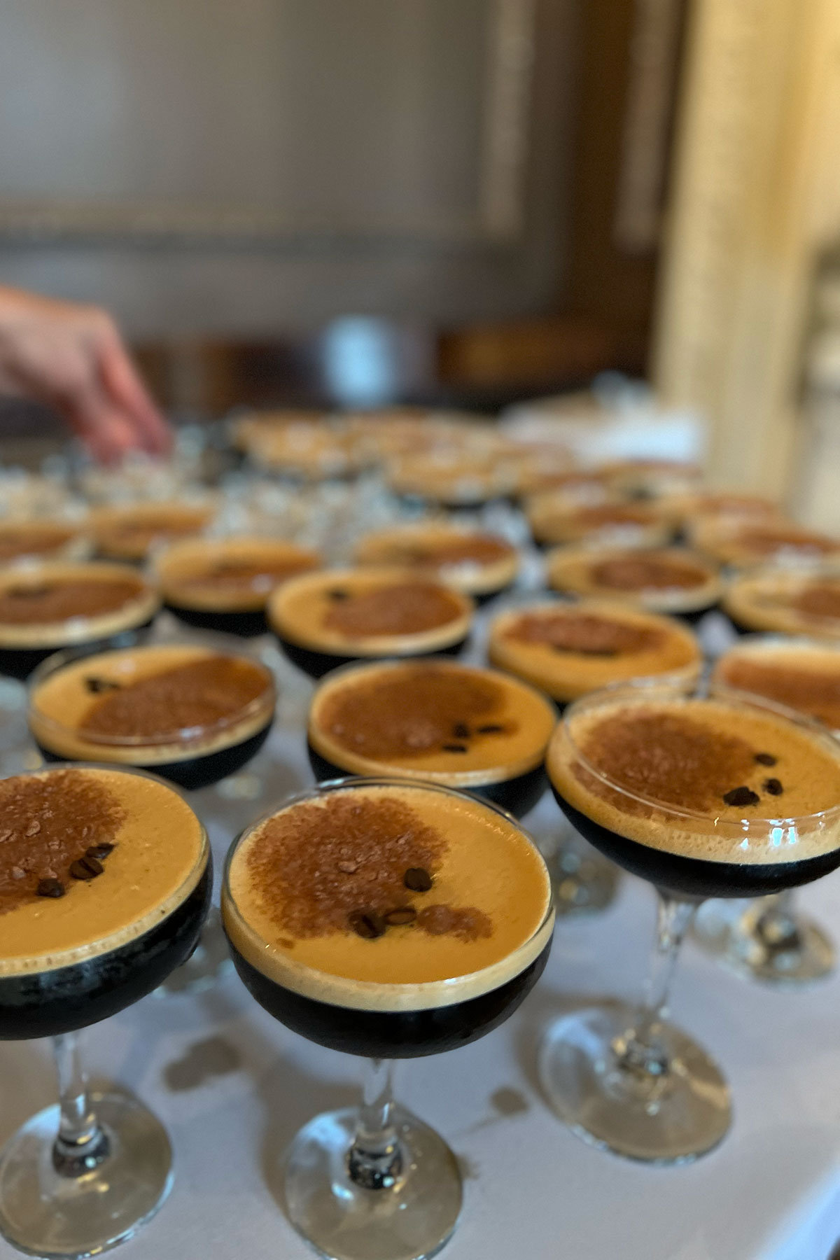 Rows of espresso martinis prepared on a serving table for wedding guests