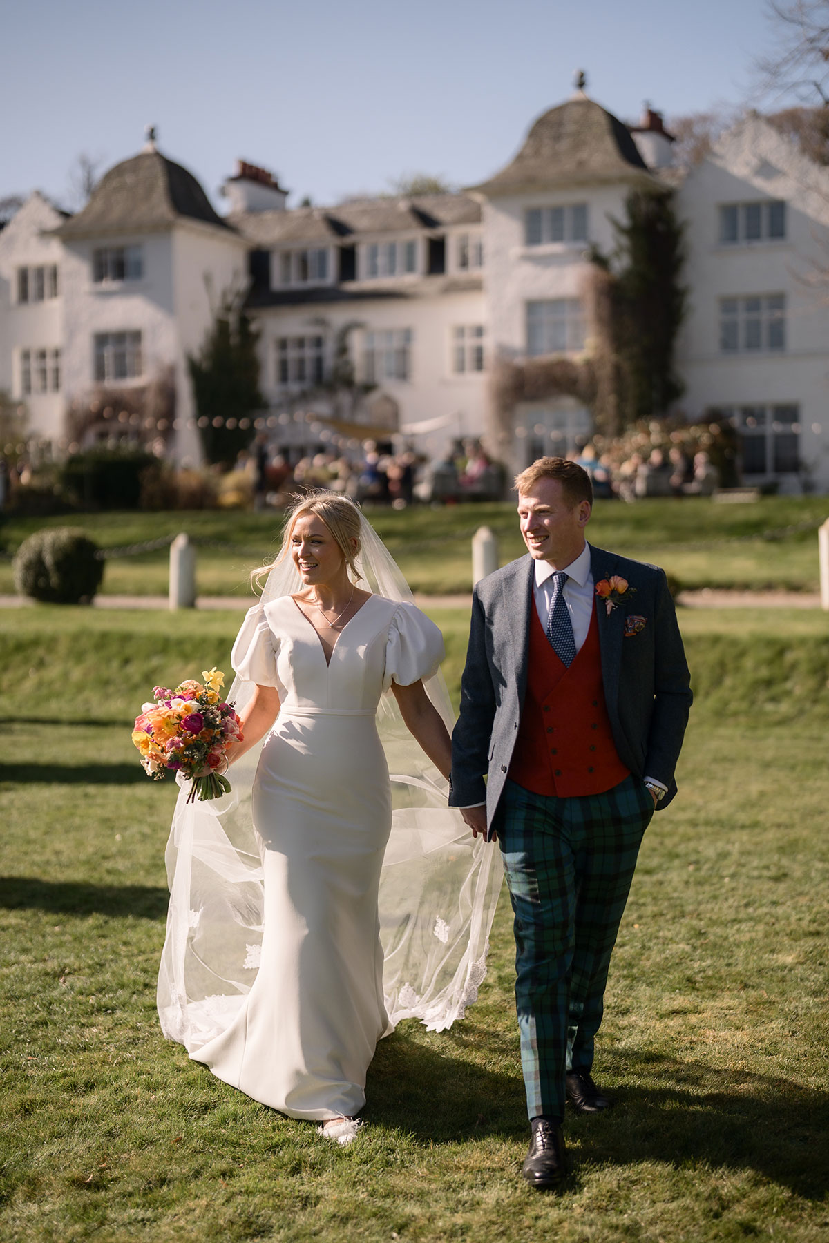 bride and groom in focus as guests party in the background during wedding at achnagairn castle