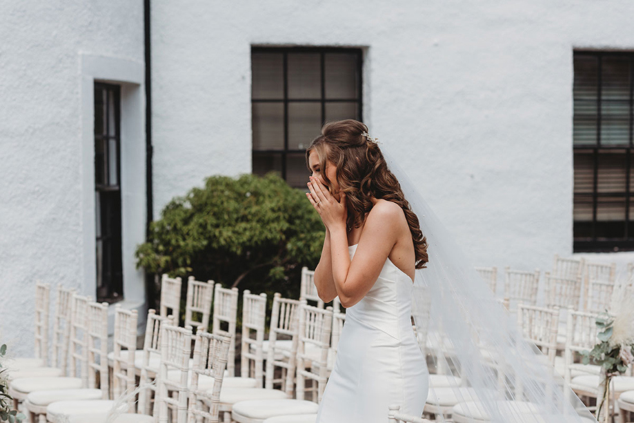 Bride covers face during her first look with soon-to-be husband