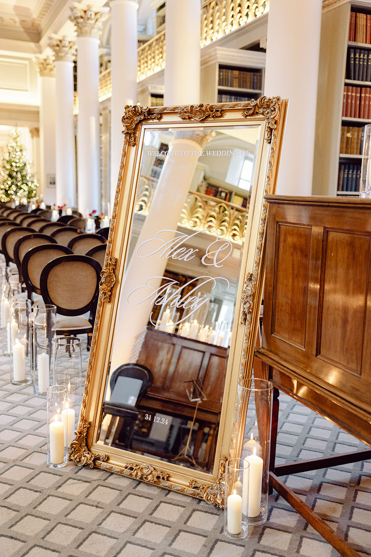 Ornate gold-framed mirror displaying the wedding welcome sign for Alex and Ashley, surrounded by candles inside The Signet Library