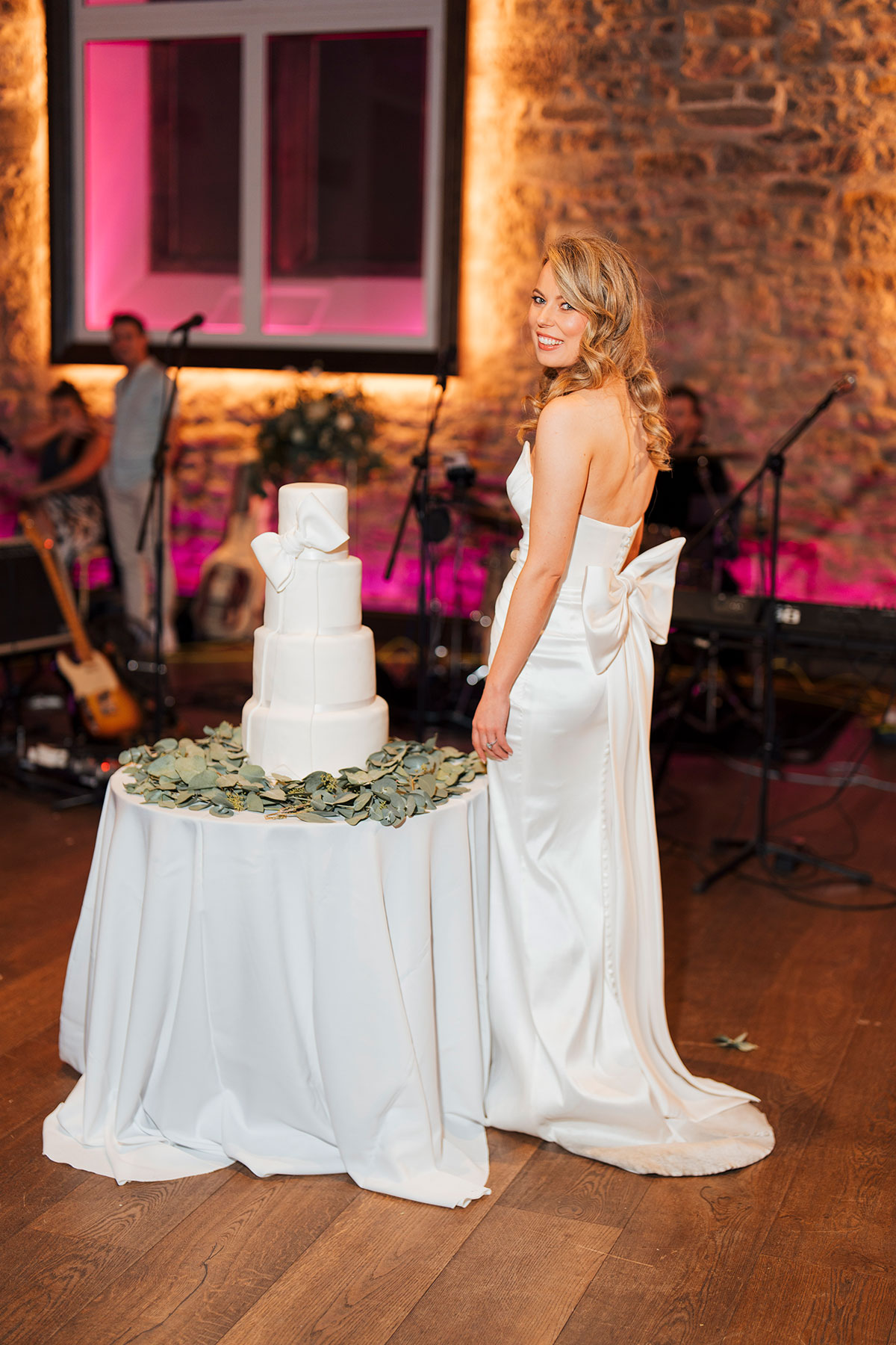 bride smiling next to cake on wedding day at Virgin Hotels Edinburgh