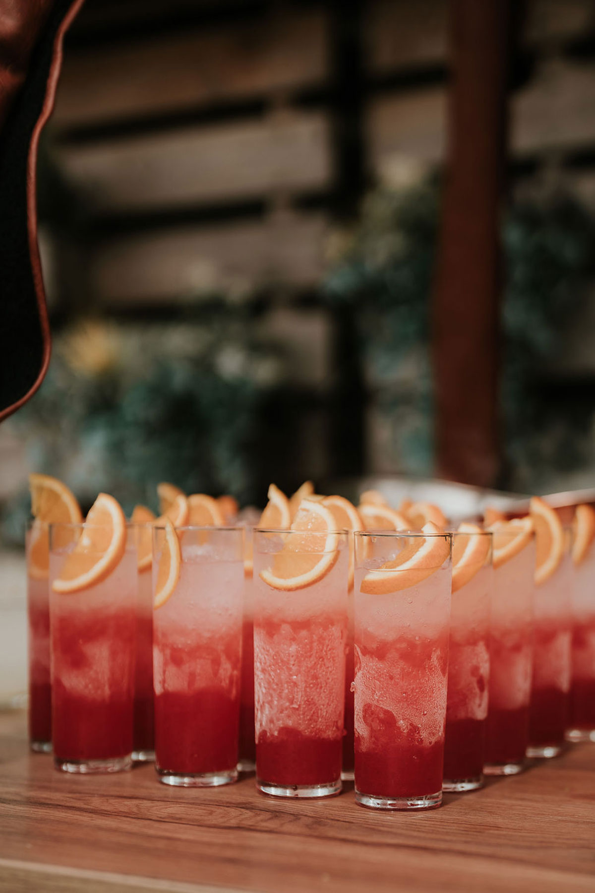 Line of signature wedding cocktails topped with fresh orange slices.