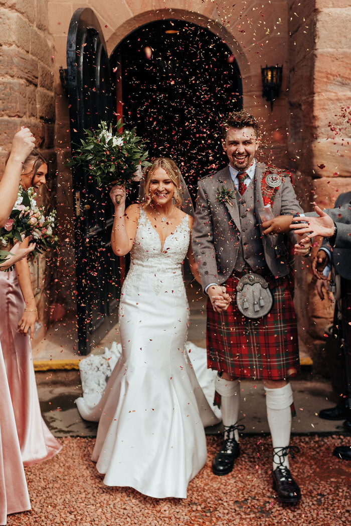 bride and groom leave Dalhousie Castle after wedding ceremony as guests throw confetti