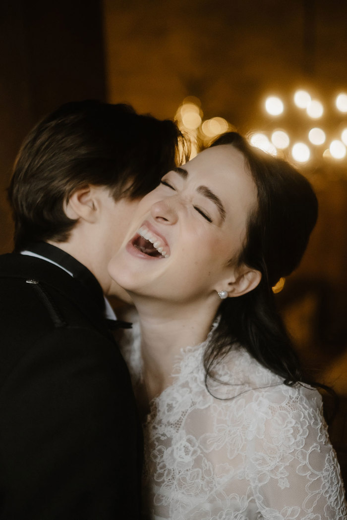 an elated laughing bride wearing a lace dress. 