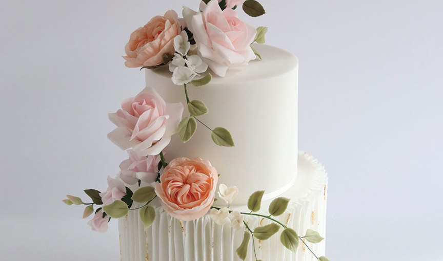 An ivory wedding cake with pink and peach sugar flowers