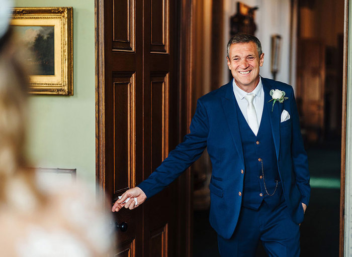 Bride's father smiles during his first look at her in her wedding dress