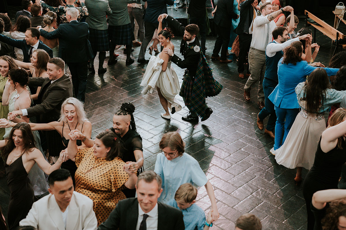 Bride and groom dancing during ceilidh at Glasgow wedding reception surrounded by guests