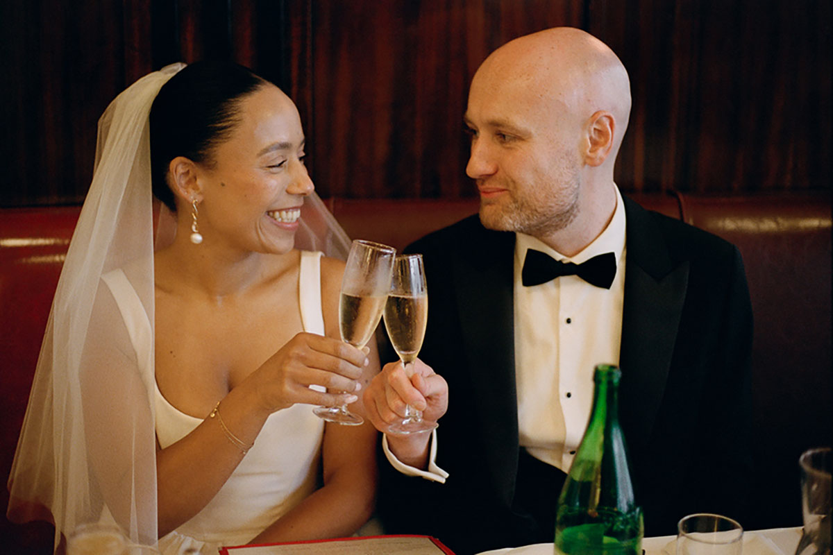 Bride and groom toasting champagne at New York wedding dinner in restaurant booth