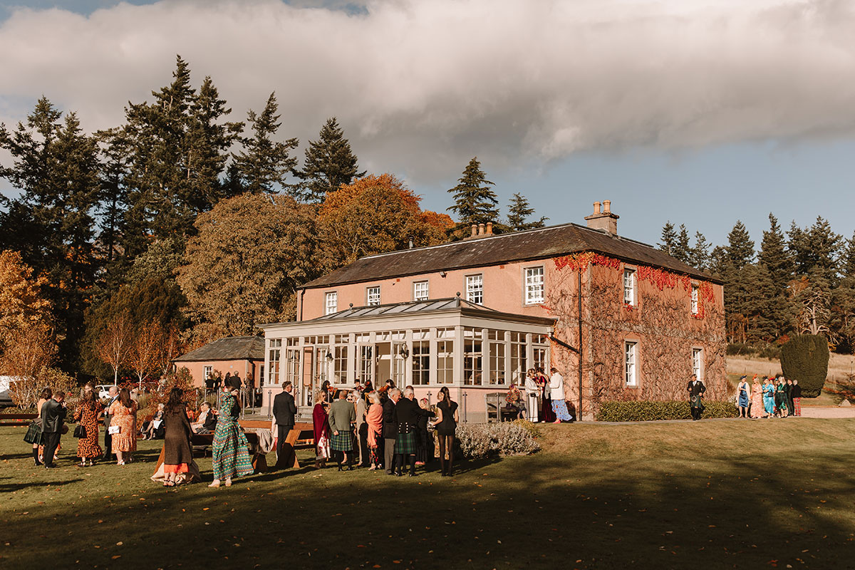 Guests gathered outside Ballogie House conservatory during autumn wedding celebrations.