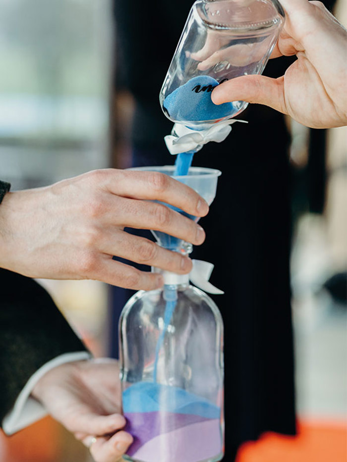 colourful sand being poured from one glass bottle into another
