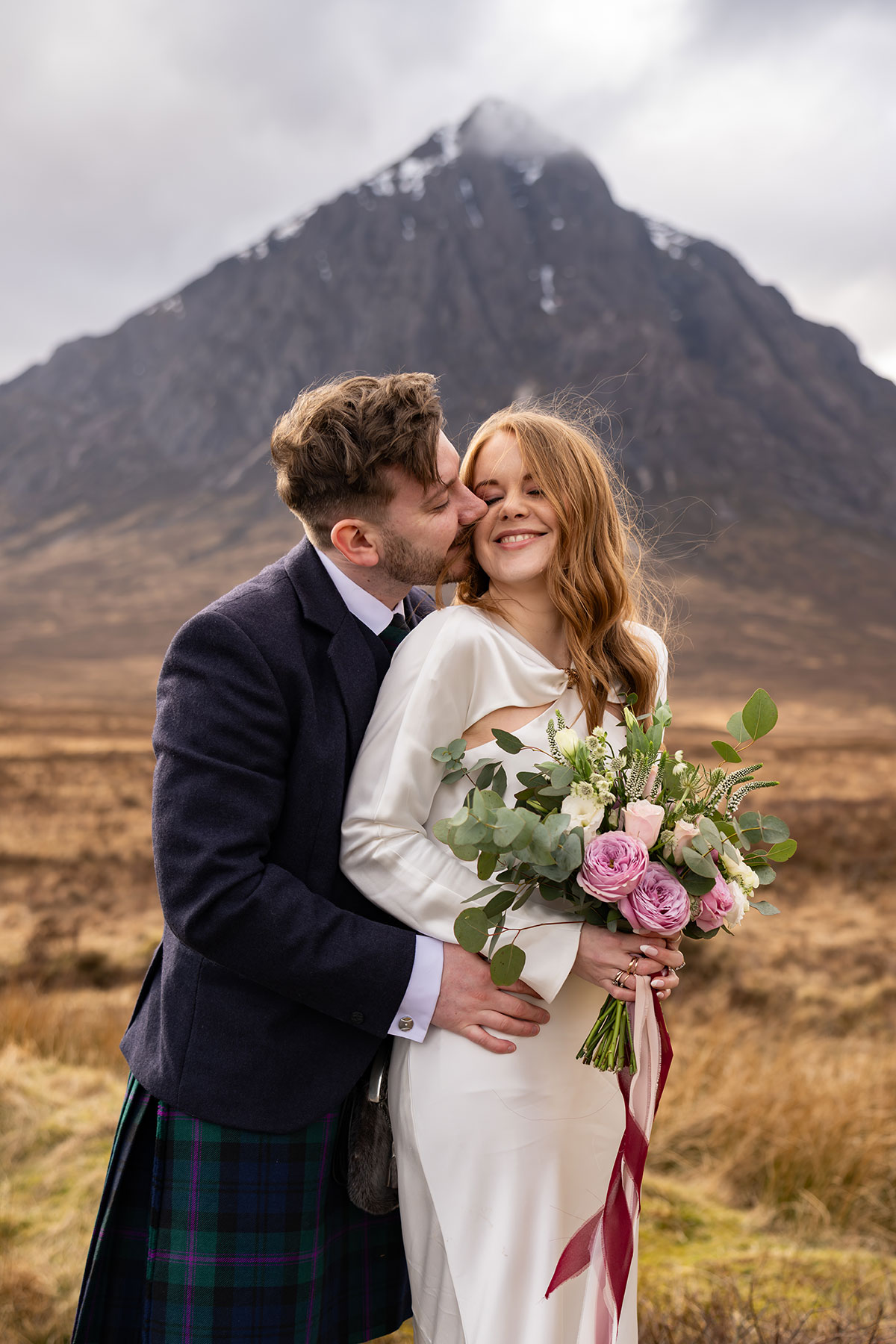 Bride and groom embracing with Buachaille Etive Mòr behind them after their romantic Glencoe elopement