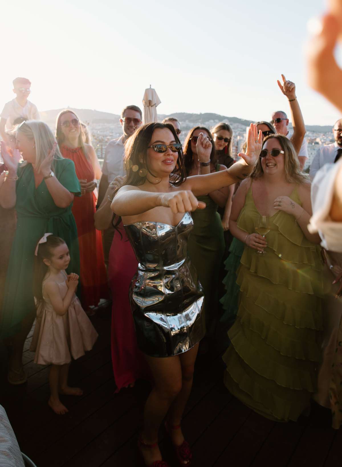 Bride in a metallic mini dress dances with wedding guests at her rooftop after-party at The Hoxton Barcelona.