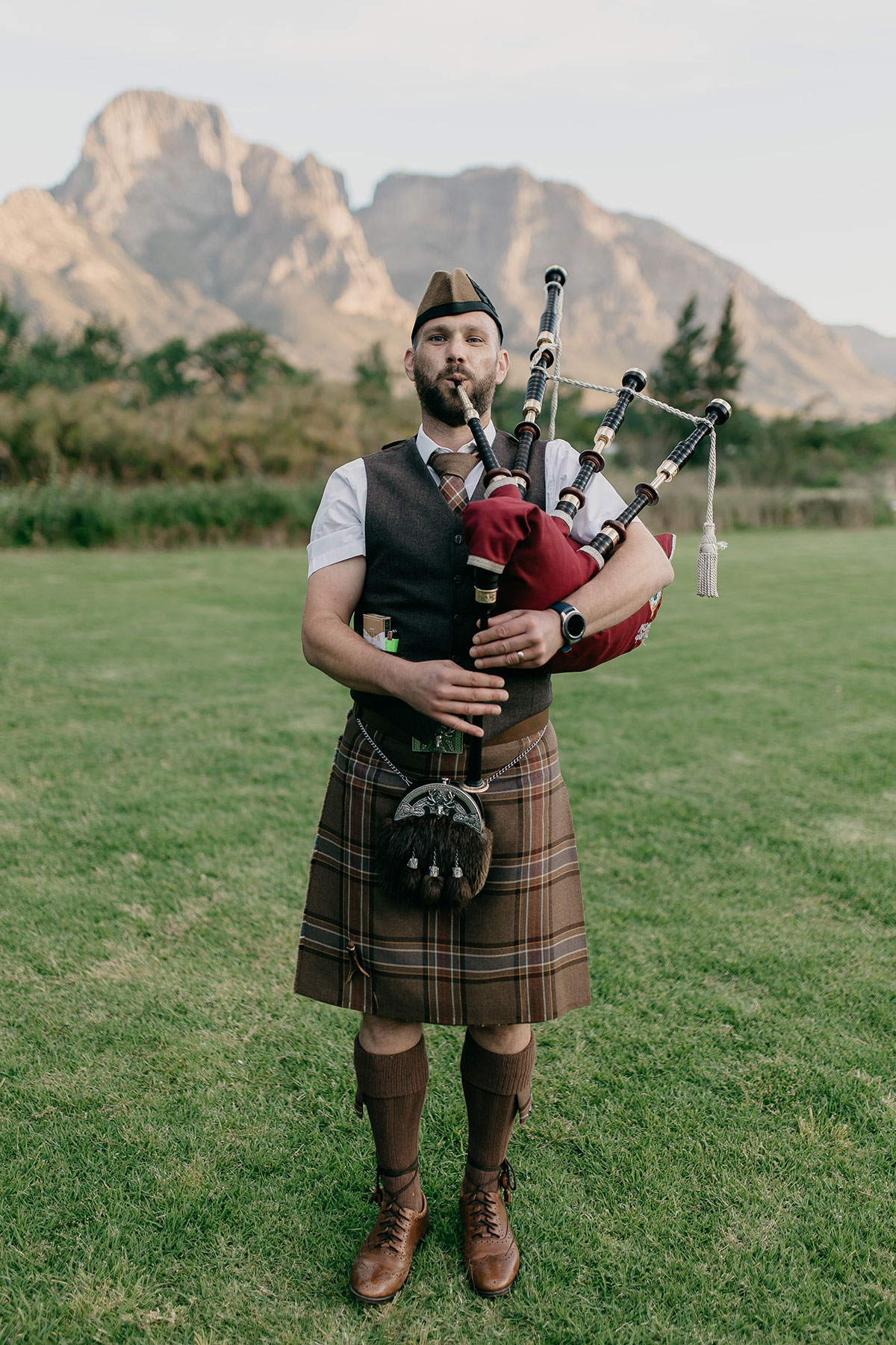 Scottish bagpiper performing at Boschendal Wine Estate wedding with Cape Town mountains in the background
