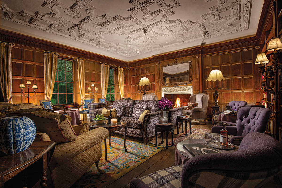 Wood-panelled lounge at Thackray House in Callander with patterned seating, ornate ceiling and open fireplace.