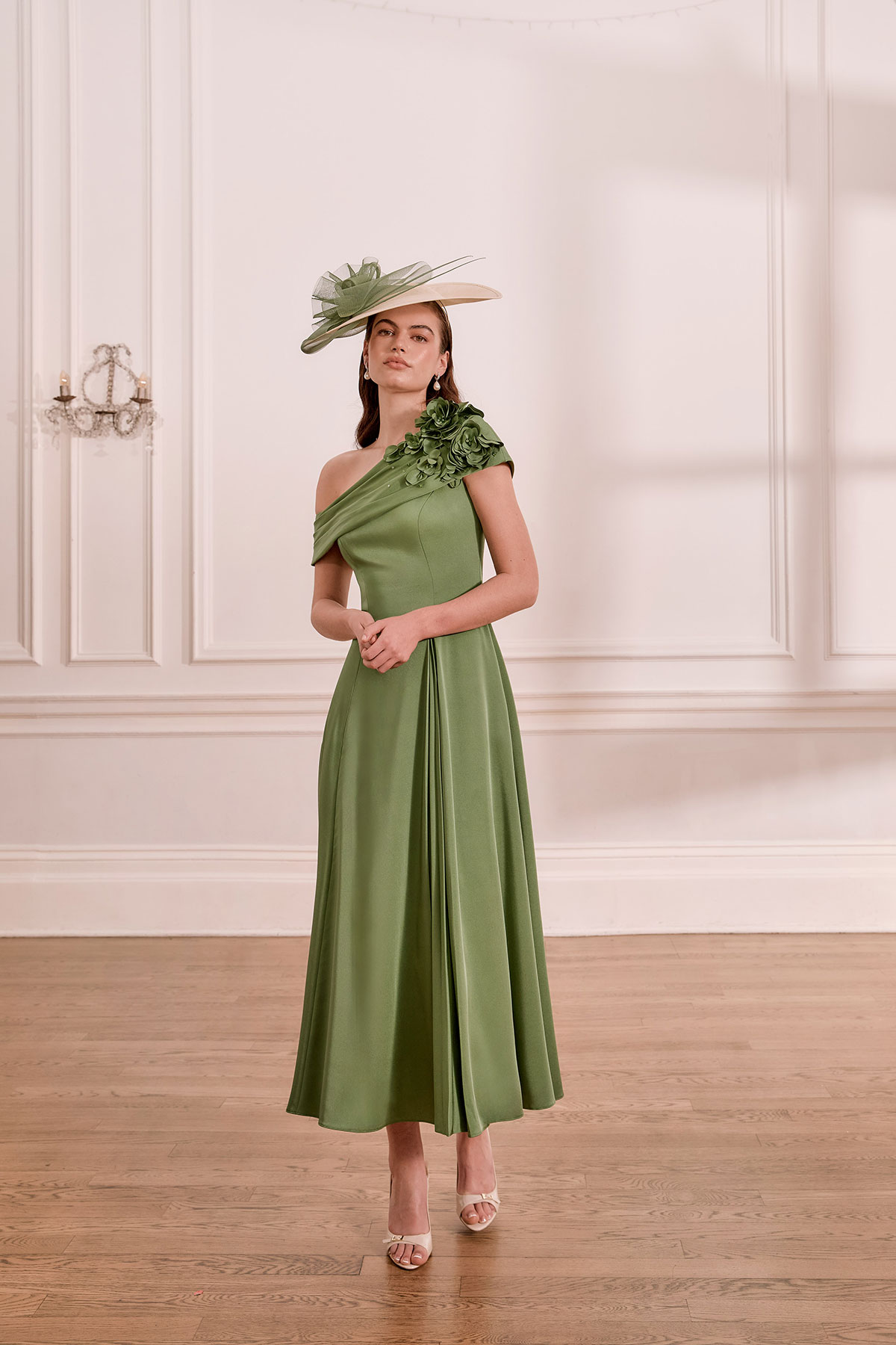 Sage green mother of the bride dress with one-shoulder floral detail and coordinating wide-brim hat.
