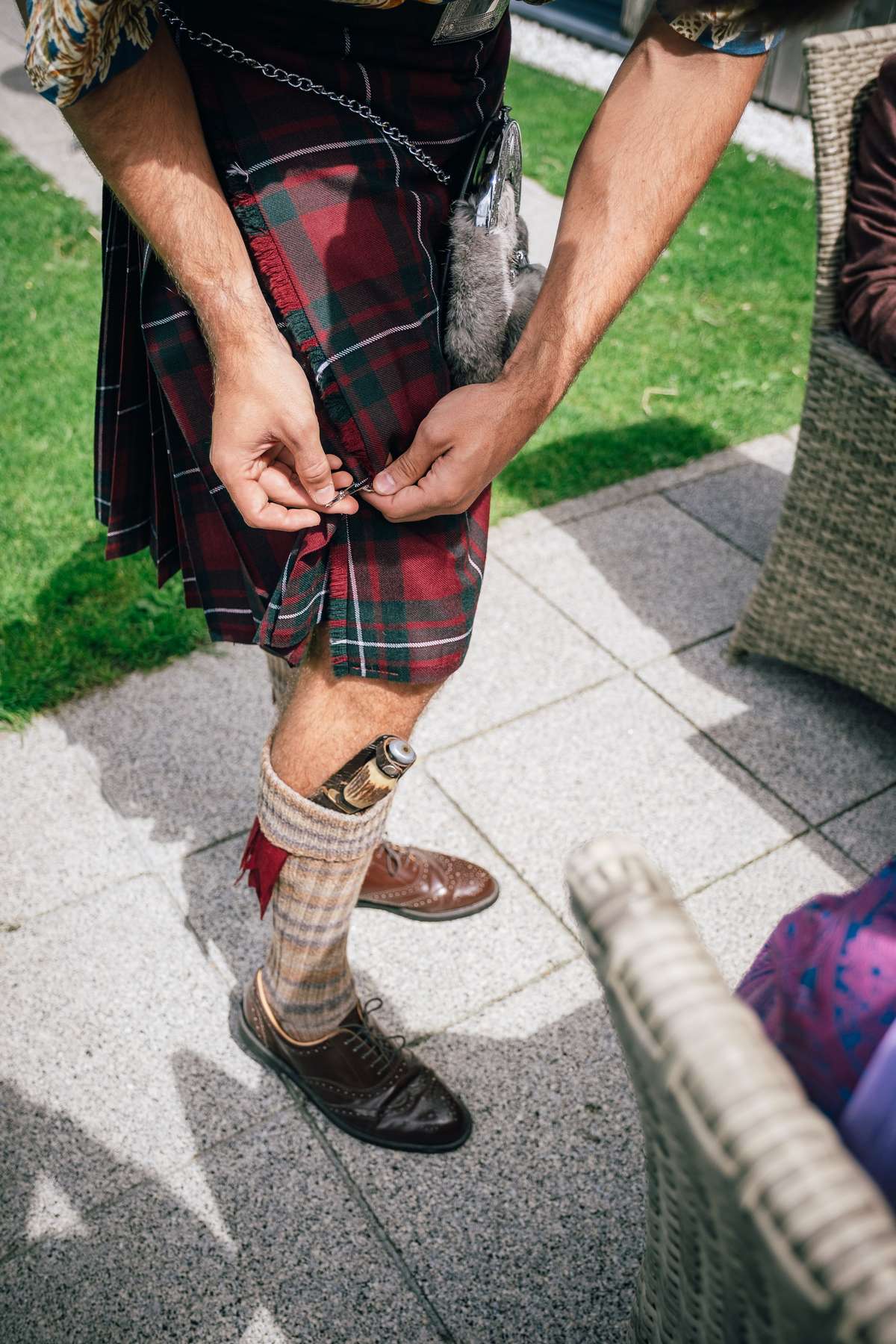 Close-up of a groom adjusting his tartan kilt during a wedding at Ardoch Loch Lomond