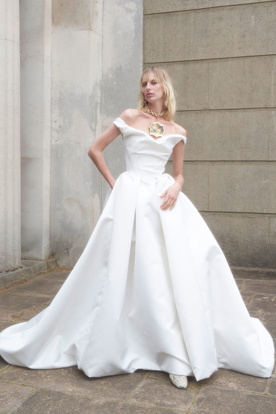 A woman wearing a Vivienne Westwood wedding dress outside a stone building.