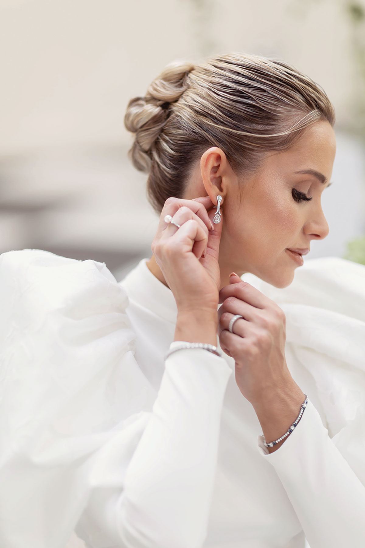 Bridal hairstylist creating sleek updo for bride during Scottish wedding shoot
