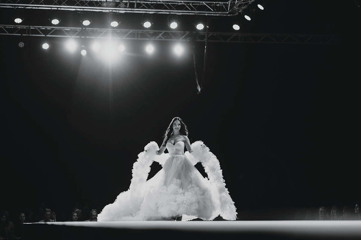 black and white picture of bride wearing a tulle wedding dress and scarf walking down the scottish wedding show catwalk