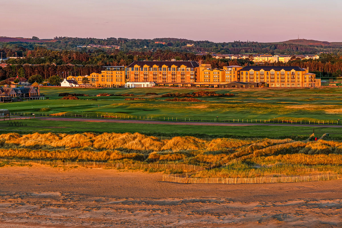 Old Course Hotel exterior overlooking golf course and coastal dunes at sunset in St Andrews, Scotland