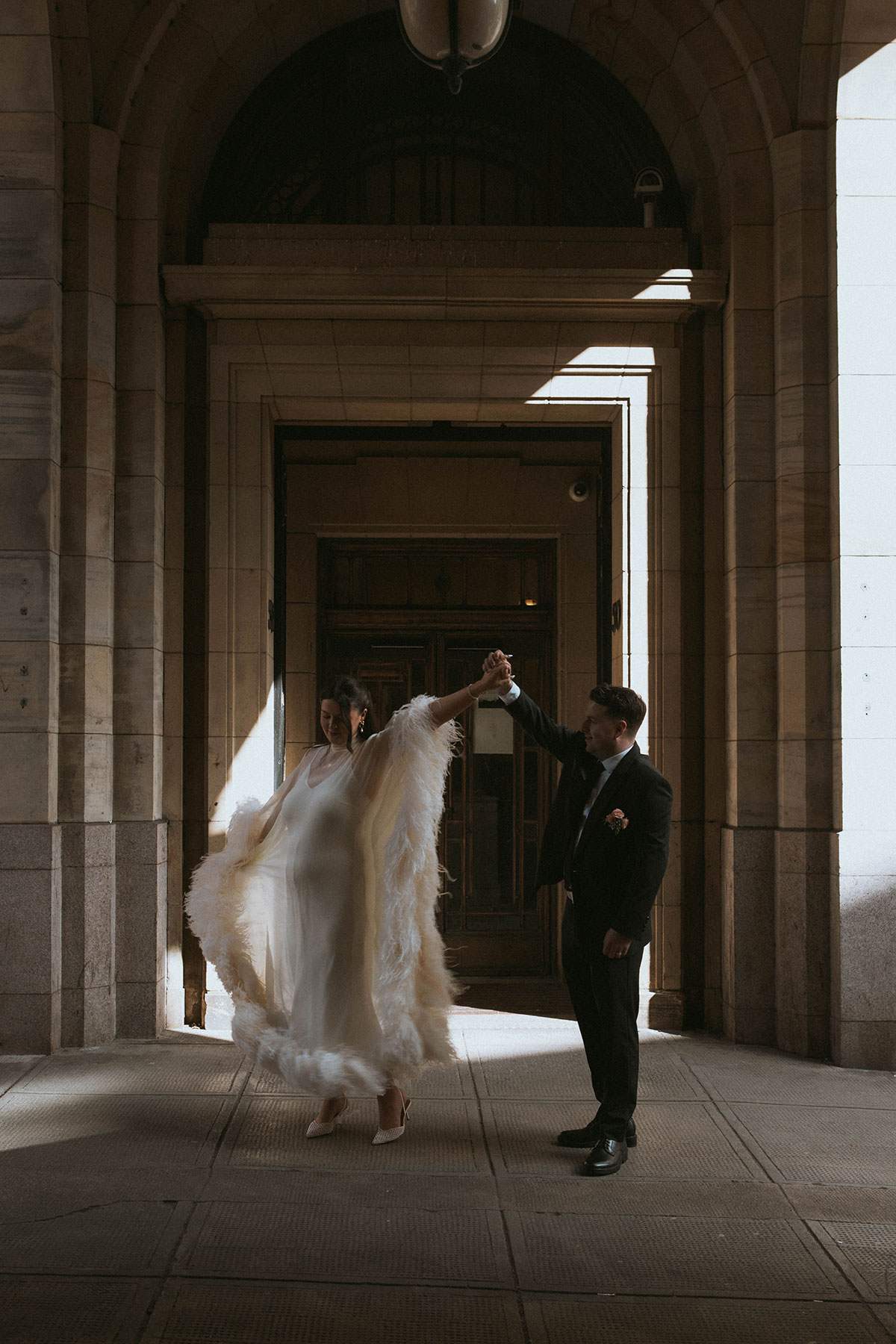 Bride and groom sharing a playful dance beneath an archway after their wedding ceremony