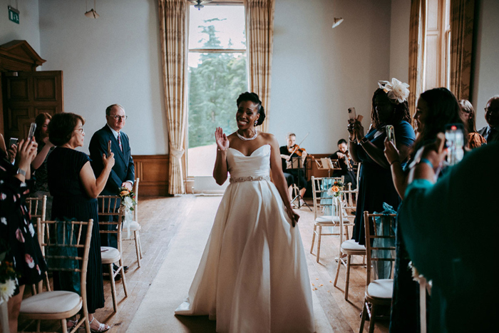 Bride walks down the aisle and waves at guests