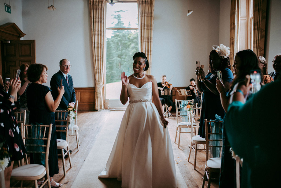 Bride walks down the aisle and waves at guests