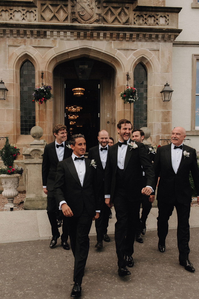 men in bow ties and tuxedos walking in a group outside Cameron House.