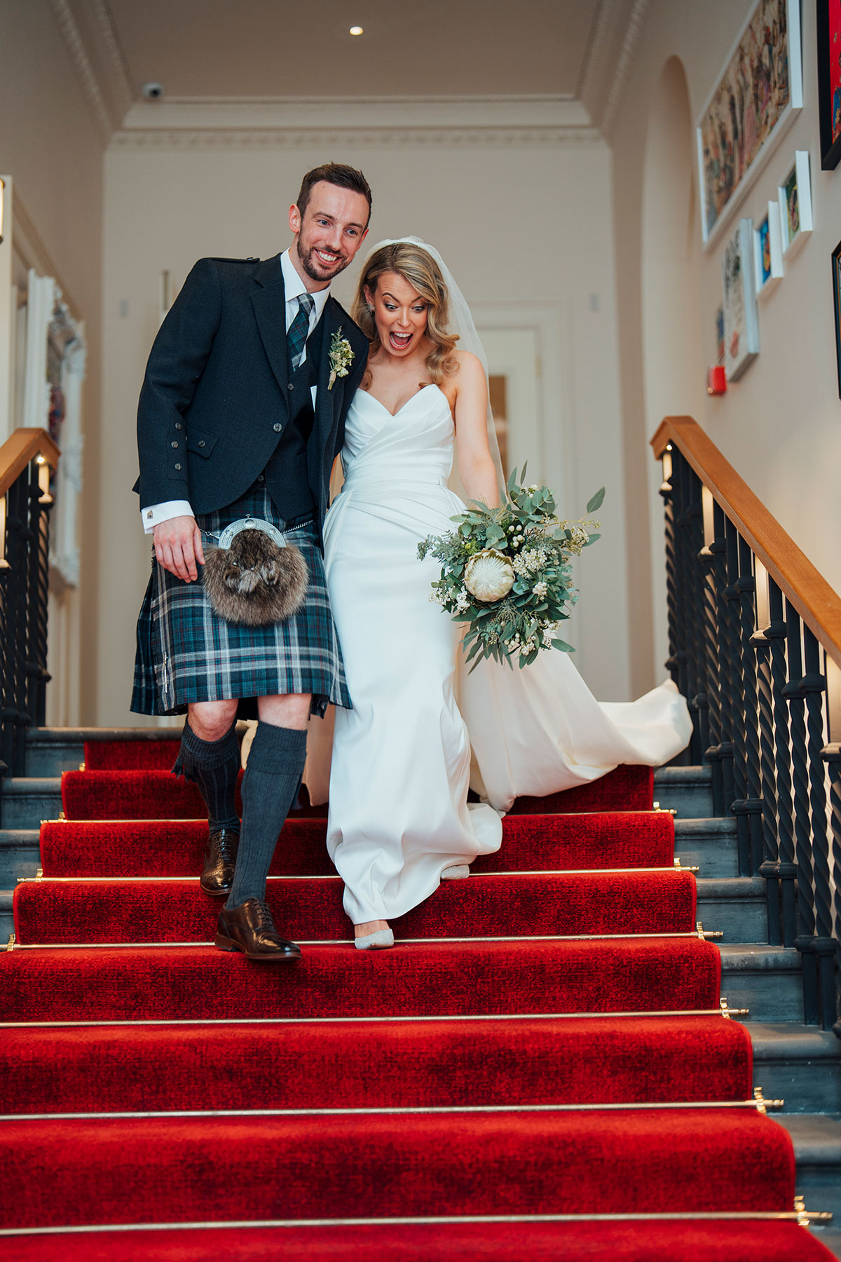 couple walk down red carpet stairs after getting married at Virgin Hotels Edinburgh