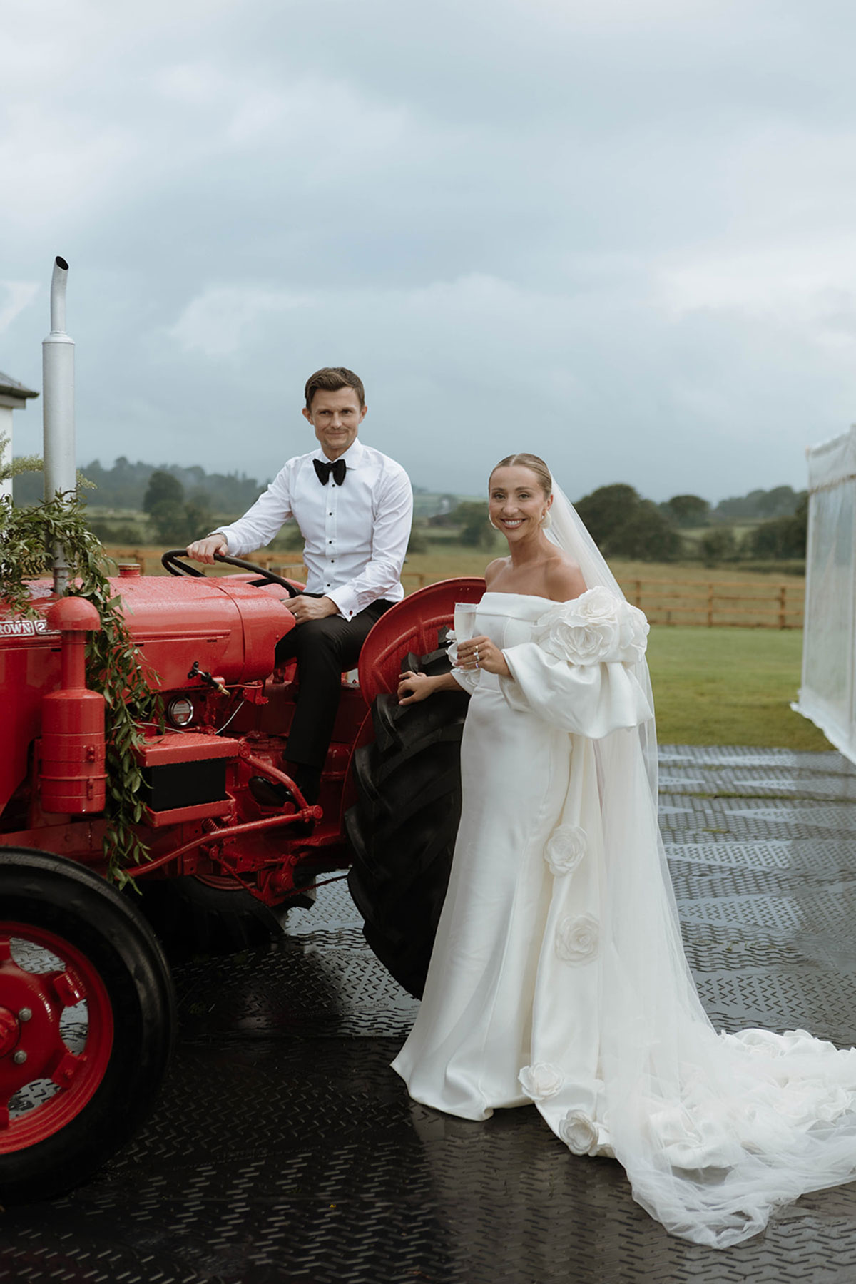 Bride and groom posing with a vintage red tractor at an Ayrshire farm wedding marquee reception