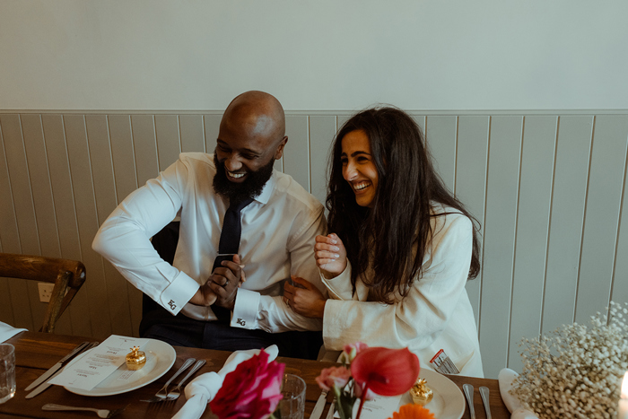 A Bride And Groom Laughing While Seated At A Table At Dougarie Boathouse