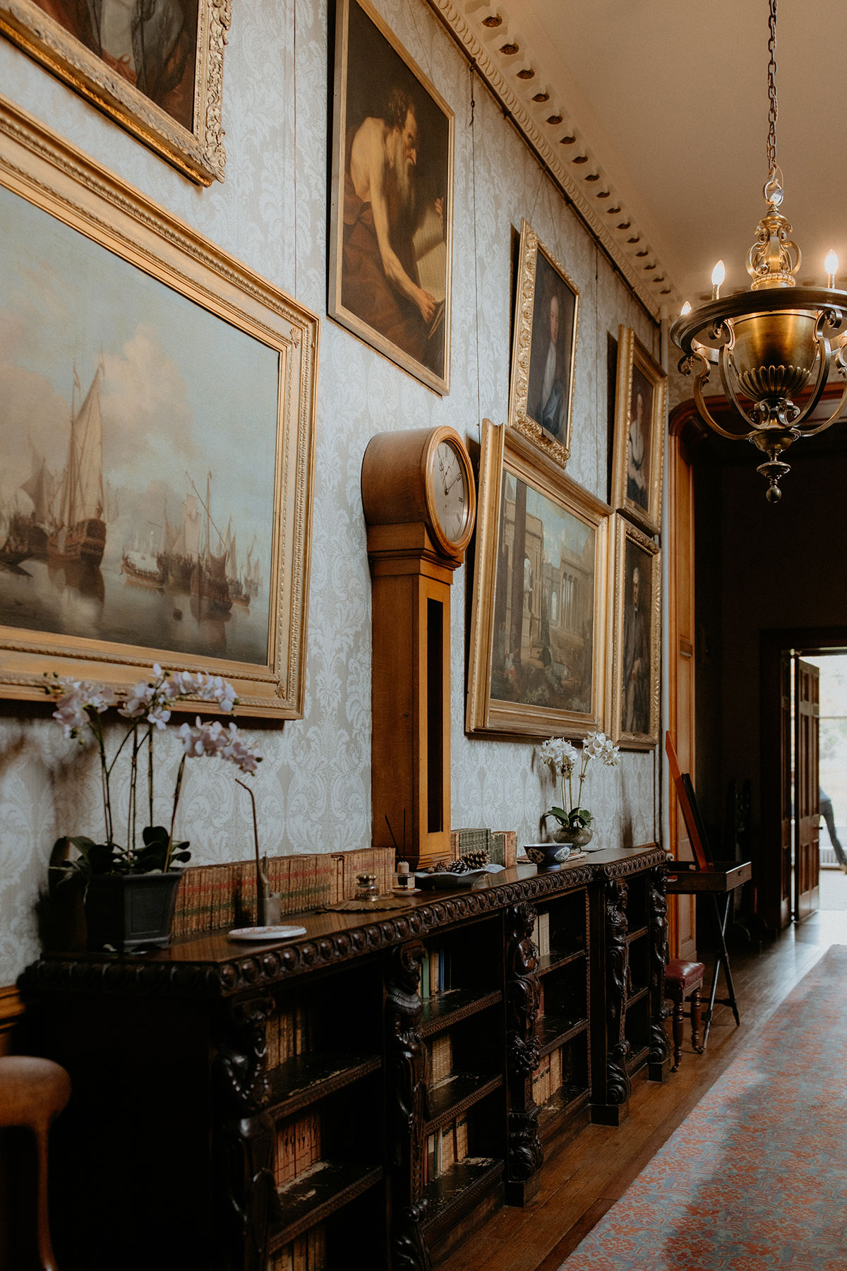 Historic hallway interiors at Cambo Estate with artwork, antique furniture and chandelier lighting