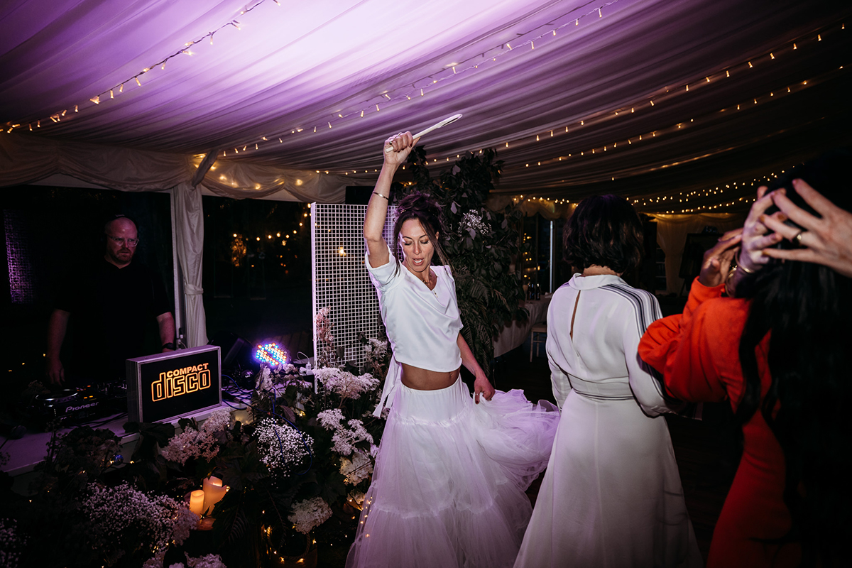 A Person Wearing A White Skirt And Top Dancing While Holding A Glow Stick