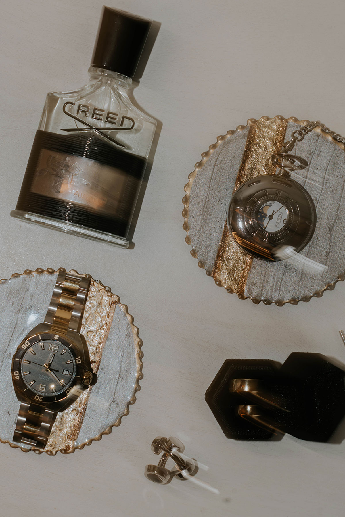 Groom accessories flatlay featuring Creed aftershave, watches, cufflinks and wedding rings