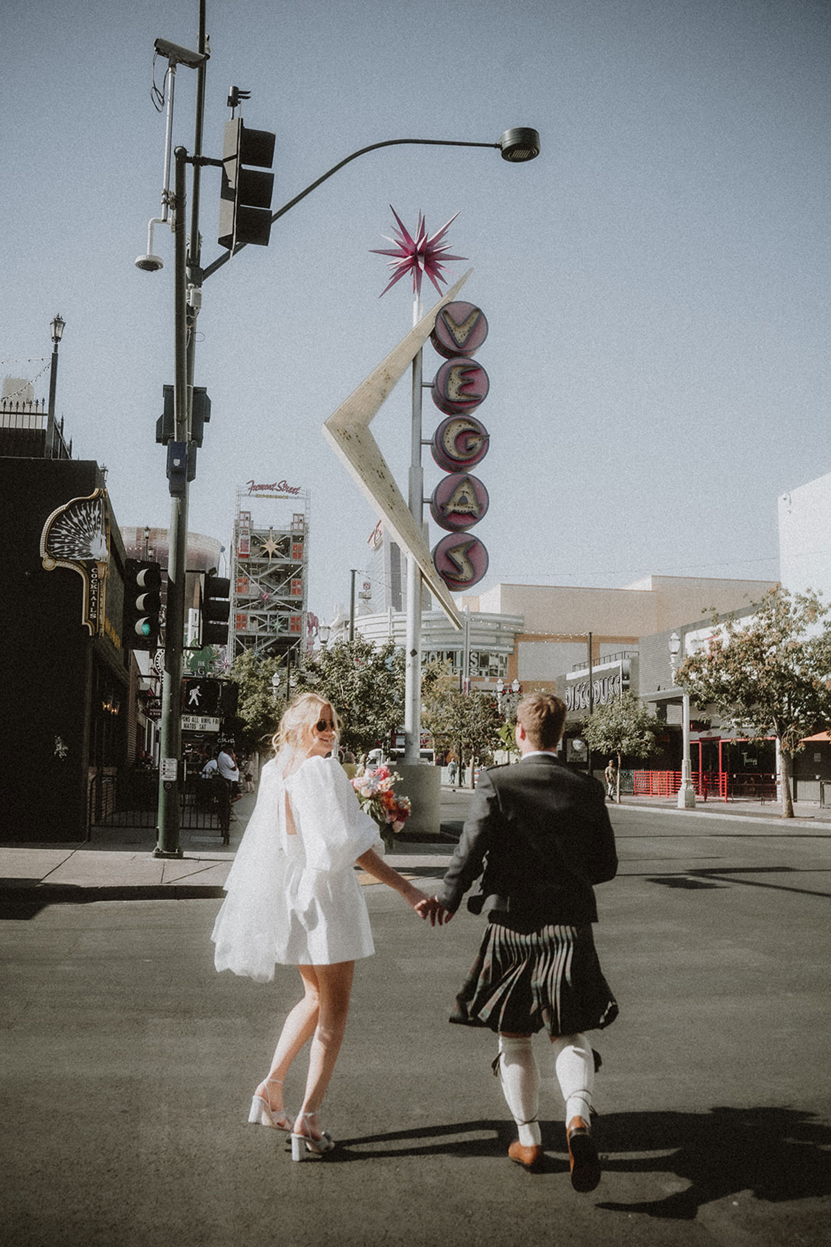 bride and groom wearing a kilt walk through the streets of las vegas after getting married