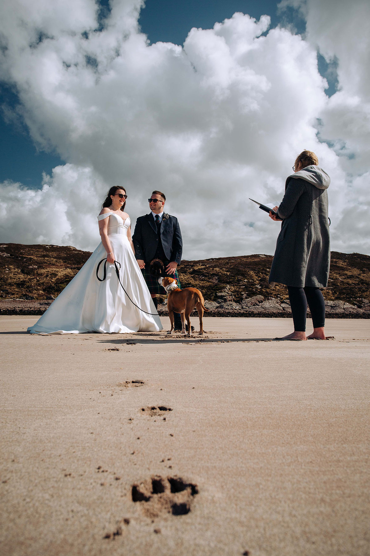 Couple exchange vows on Achnahaird Bay with their celebrant and dog under dramatic Highland skies.