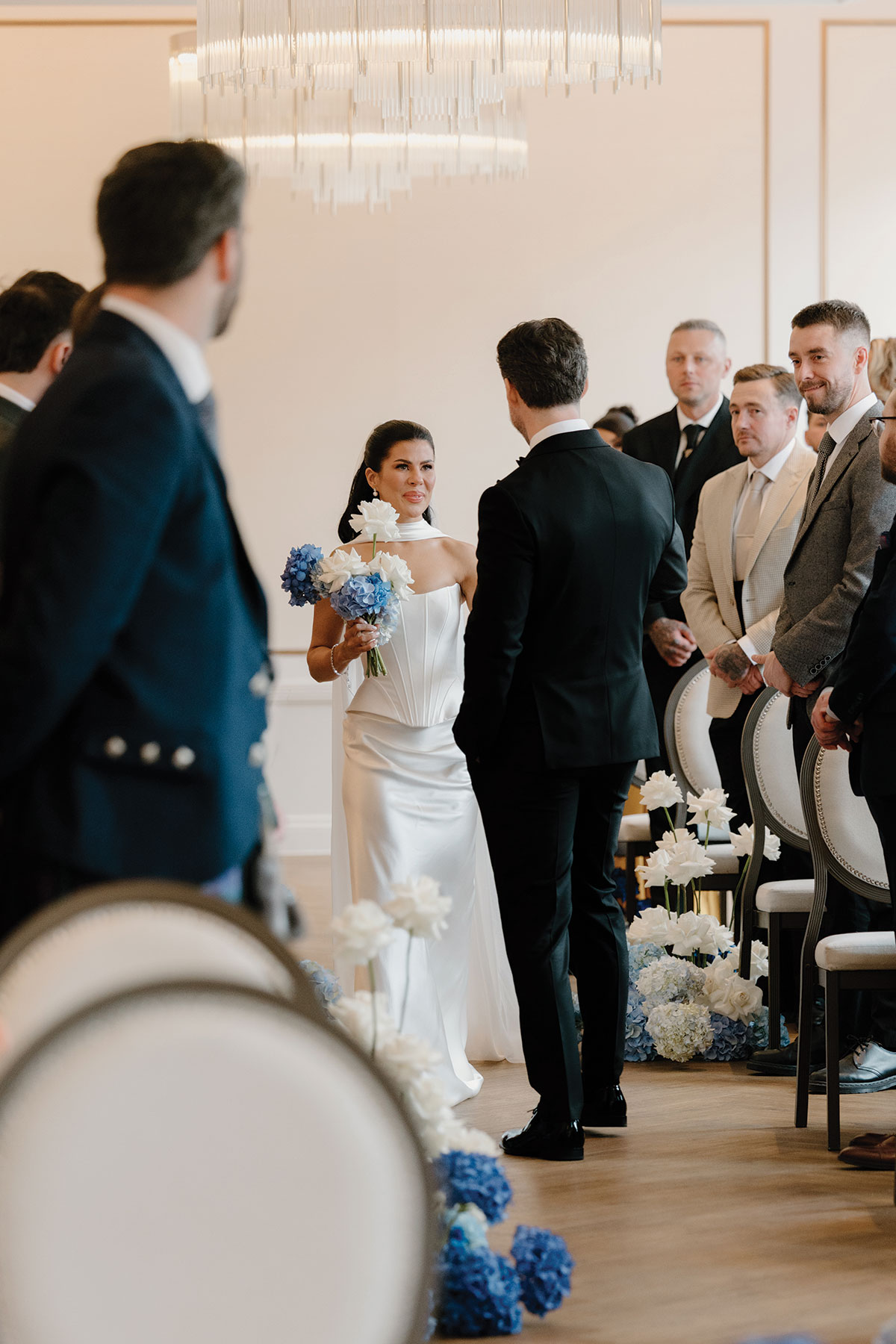 Bride walks down the aisle during modern wedding ceremony at The Exchange with blue and white floral arrangements