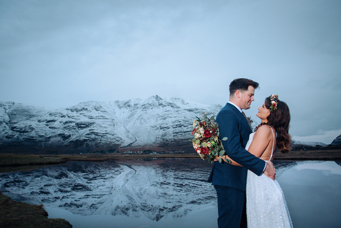 Bride and groom pose in front of snow-capped mountain